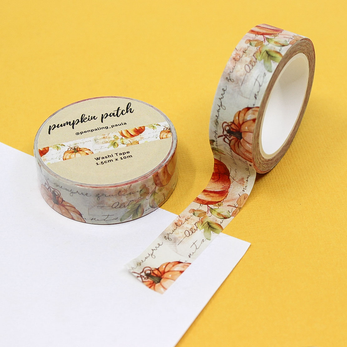 Washi tape featuring a pumpkin patch design over a cursive journaling background, with warm orange and cream autumn tones.